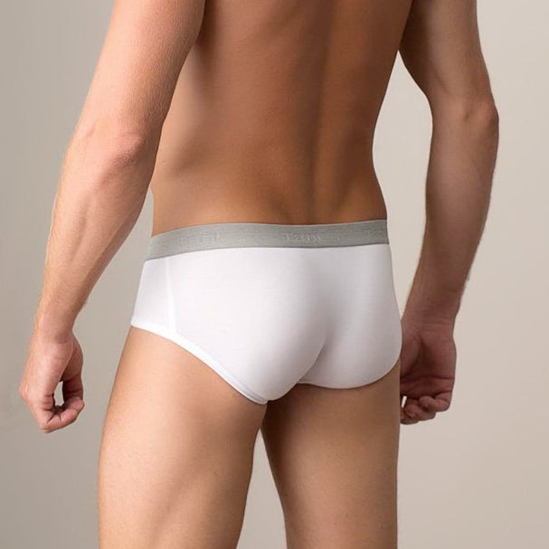 Man wearing white underwear against a beige background