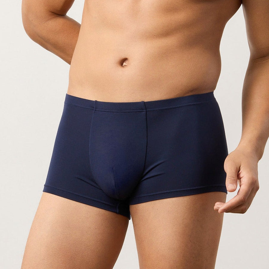Man wearing navy blue boxer briefs against a plain background