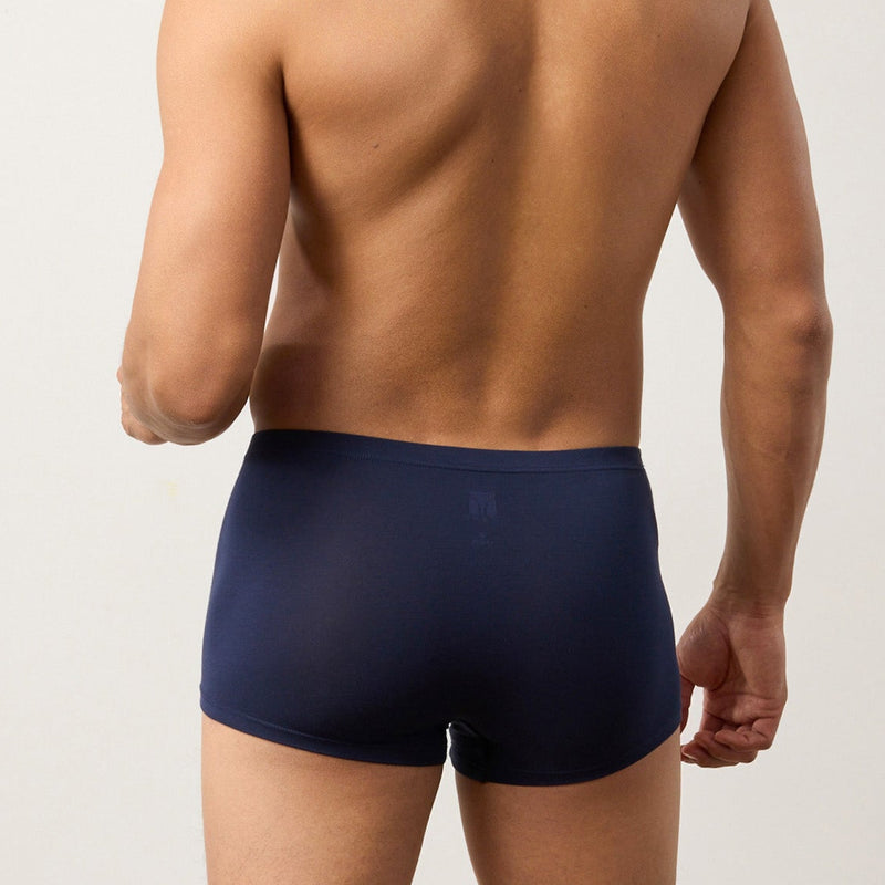 Man wearing navy blue boxer briefs against a plain background