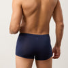 Man wearing navy blue boxer briefs against a plain background