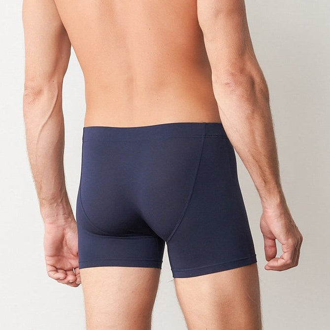 Man wearing navy blue boxer briefs on a plain background