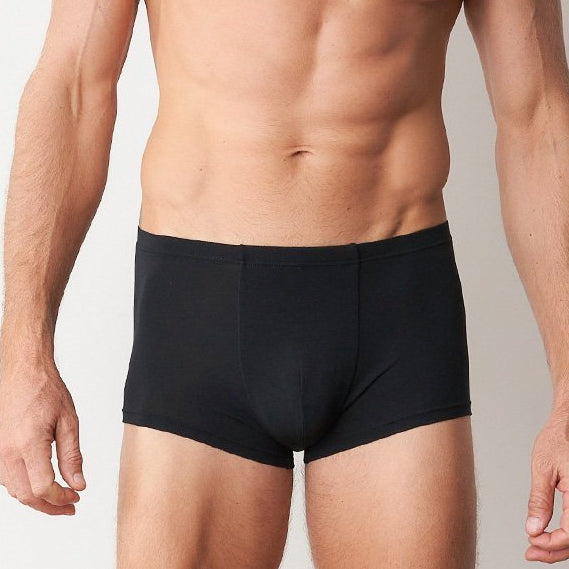 Man wearing black underwear against a plain background